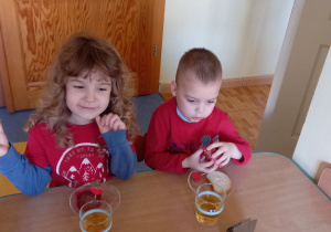 Dwóch chłopców siedzi przy stole, na talerzach mają babeczki ozdobione serdeuszkiem.