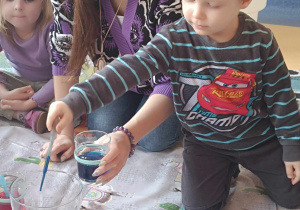 Dzieci przeprowadzają doświadczenie z barwnikami i oliwą.