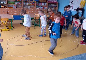 Dzieci chodzą po linach ułożonych na podłodze w kształcie pisanki.