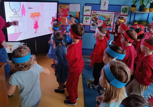 Urodziny Kropelki. Dzieci powtarzają ruchy bohatera pokazanego dużym ekranie multimedialnym.