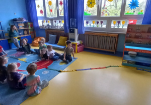 Dzieci układają na podłodze kolorowego węża z szarf gimnastycznych.