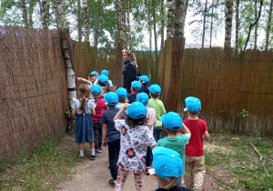 Dzieci w niebieskich czapkach z daszkiem pokonują labirynt.