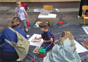 Dzieci malują farbami duże tarcze rycerskie.