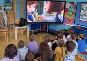 Dzieci oglądają film na dużym ekranie o dziewczynce i niepełnosprawnym chłopcu.