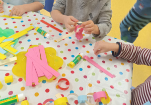 Dzieci tworzą wspólny łańcuch choinkowy z papieru