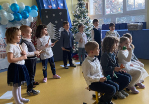 Dzień Babci i Dziadka. Czworo dzieci siedzi na krzesełkach i gra na dzwonkach.