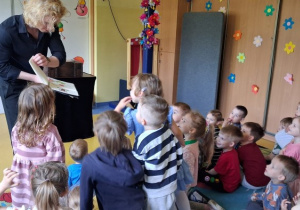 Dzieci zaglądają do czarodziejskiej księgi iluzjonisty.