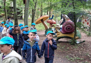 Wycieczka. Dzieci spacerują wśród figur dużych grzybów.