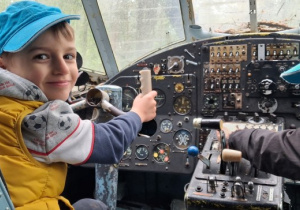 Wycieczka. Dwóch chłopców siedzi w kabinie pilotów w samolocie.