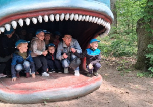 Wycieczka. Dzieci siedzą w paszczy sztucznego wieloryba.