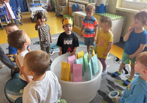 Jeden chłopiec stoi w koronie a reszta dzieci stoi wokół niego.