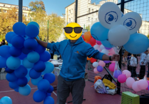 Rodzic trzyma balony z motywem kropelki oraz girlandę z niebieskich balonów.