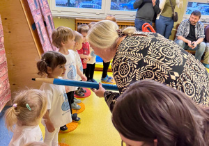 Pani Dyrektor ma duży ołówek w ręku i pasuje najmłodsze dzieci na przedszkolaka.