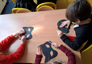 Dzieci ozdabiają maski wydrapując wzory.