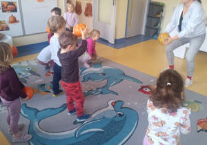 Dzieci trzymają w ręku dynie.