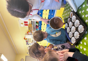 Pani wlewa ciasto do foremek na babeczki.