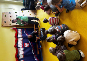 Dzieci siedzą na podłodze i biorą udział w koncercie muzycznym.