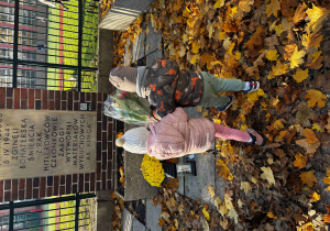 Dzieci kładą kwiaty pod pomnikiem.