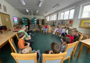 Dzień postaci z bajek w szkolnej bibliotece, dzieci słuchają czytanek ksiażki.