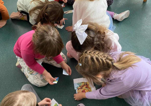 Dzień postaci z bajek w szkolnej bibliotece, dzieci układają puzzle.