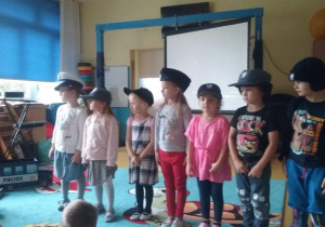 Dzieci stoją w czapkach policjanta.