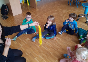 Dzieci uczą się wydmuchiiwać powietrze przez słomkę aby poruszyć wstążkami