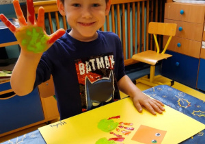 Chłopiec maluje dłonią gąsiennice.
