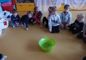 Dzieci wrzucają monety do miski z wodą.