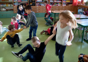 Dzieci ćwiczą w parach na podłodze.