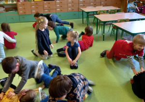 Dzieci ćwiczą wparach na podłodze.