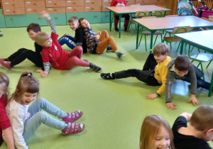 Dzieci ćwiczą w parach na podłodze.